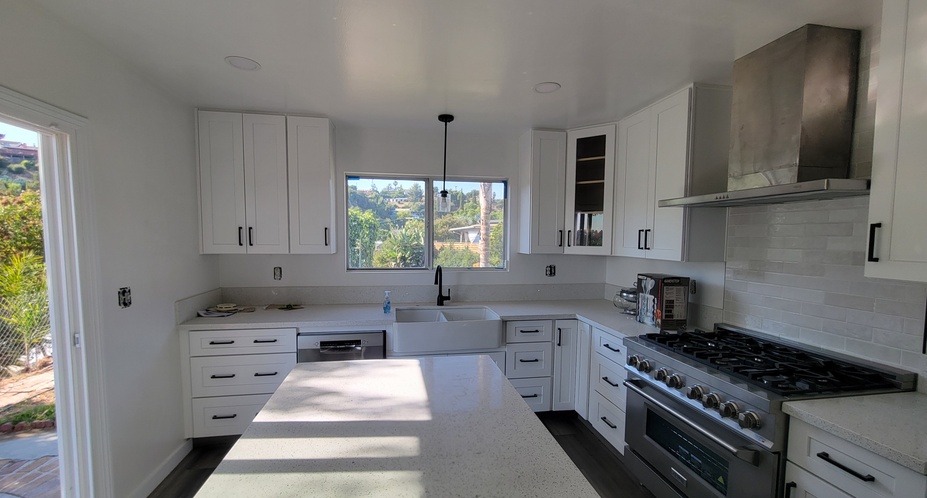 Modern white kitchen remodel with shaker cabinets, quartz countertops, and updated lighting