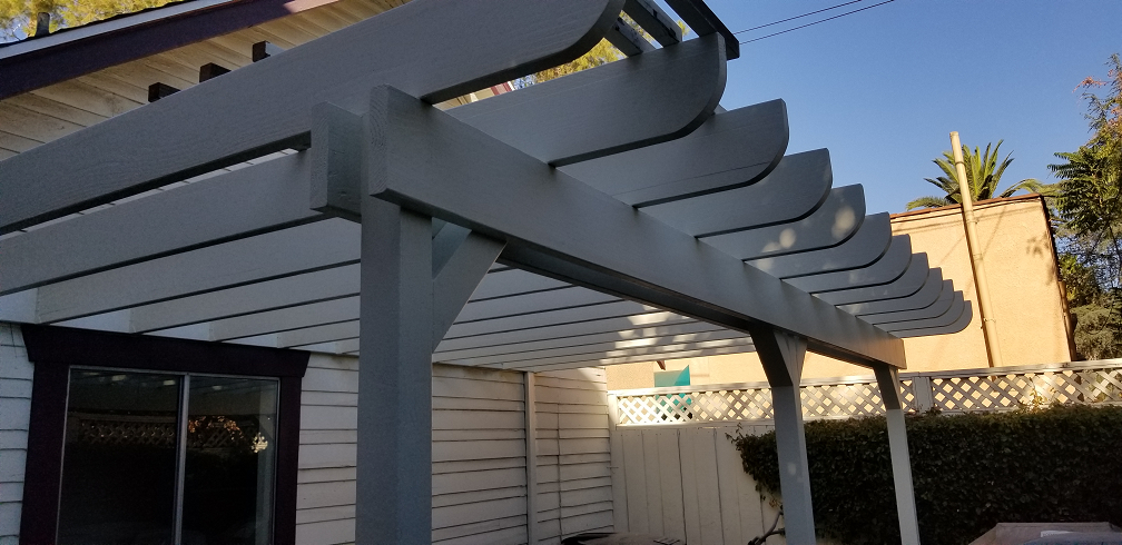 Custom outdoor pergola construction with wood beams providing shade over backyard patio