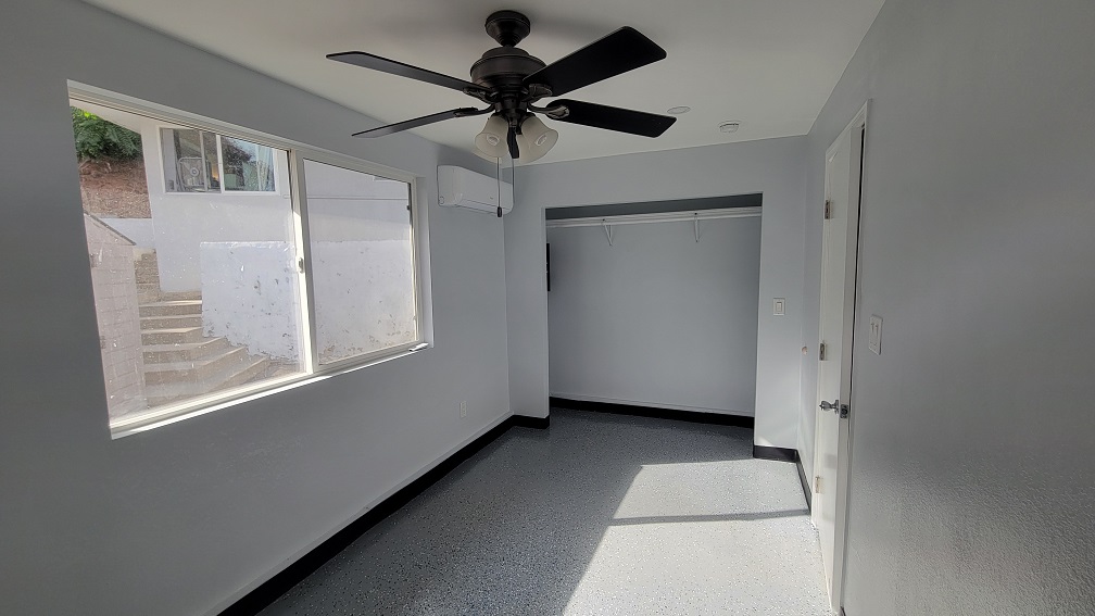 Completed ADU bedroom featuring fresh paint, new flooring, and ceiling fan installation.