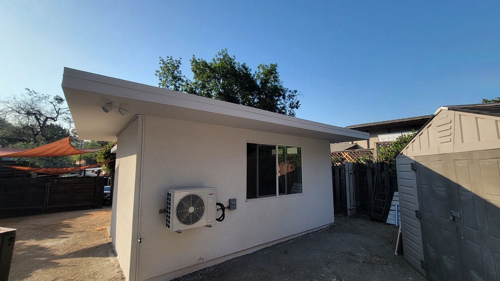 Newly built ADU exterior with fresh stucco, energy-efficient windows, and mini-split HVAC unit.