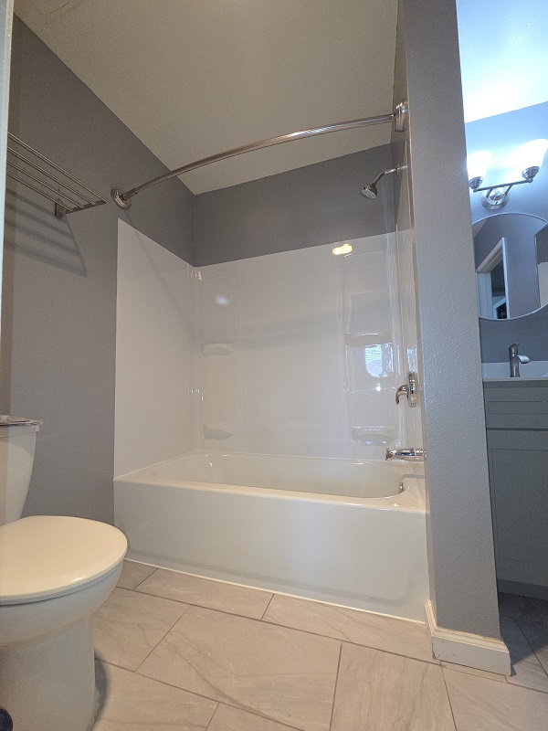 Finished bathroom remodel with new tub, shower walls, and chrome fixtures.