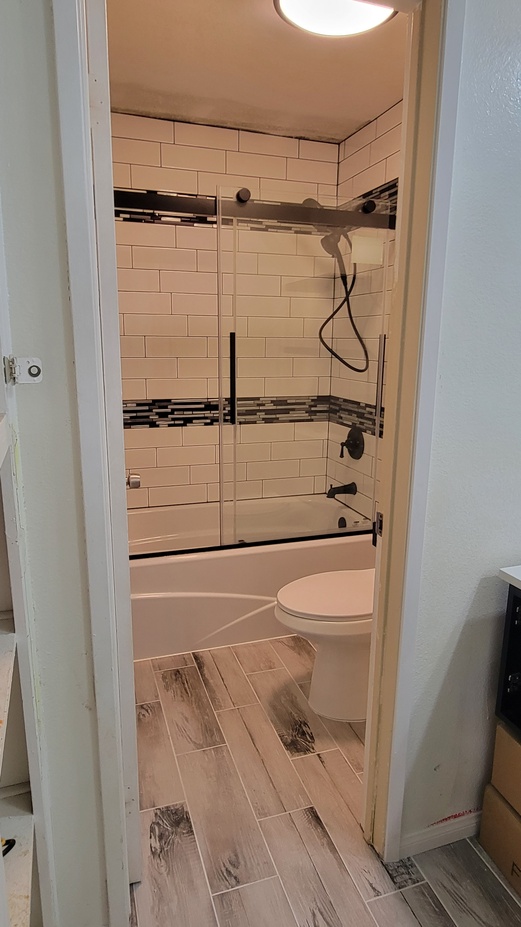 Bathroom remodel showing updated bathtub, custom tile wall, and modern fixtures.
