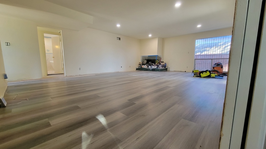 Large living room remodel with new flooring, recessed lighting, and smooth wall finishes.