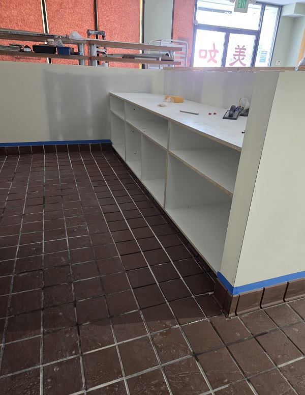 Commercial workspace renovation featuring new shelving, tile installation, and fresh paint.
