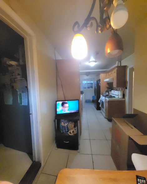 Old kitchen before remodel with outdated cabinets, tile flooring, and enclosed layout.
