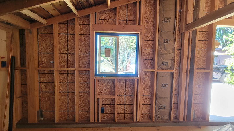 Home addition framing with new wall studs and window installation.